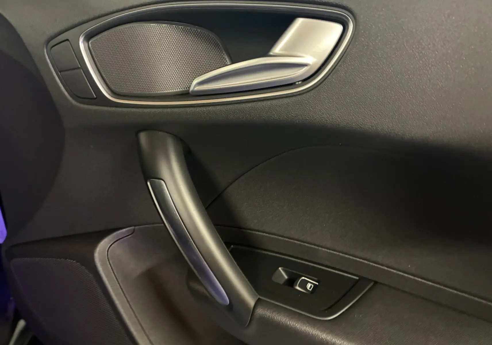 Détail de la poignée intérieure côté gauche de la porte noire d'une Audi A1 2016 avec bouton de commande de vitre.