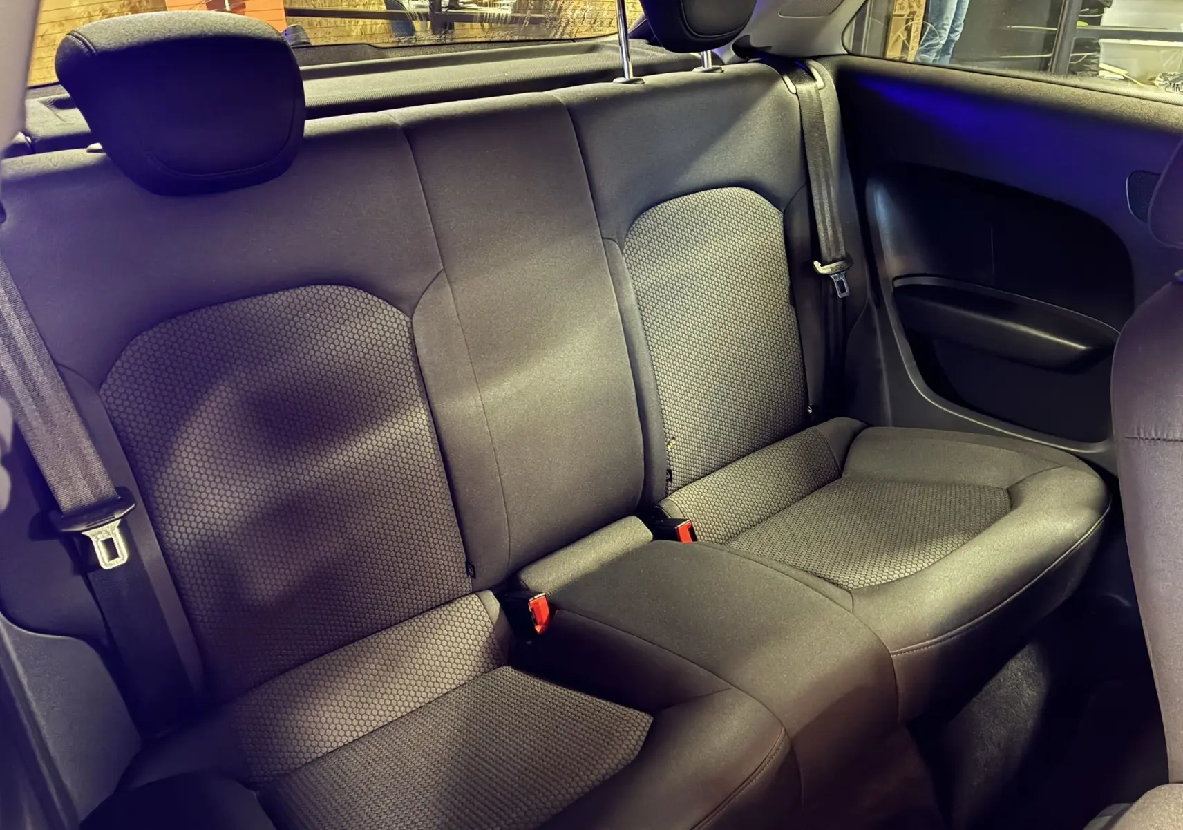 Vue intérieure arrière de l'Audi A1 2016, sièges en tissu gris noir avec ceinture de sécurité et appuie-têtes visibles.