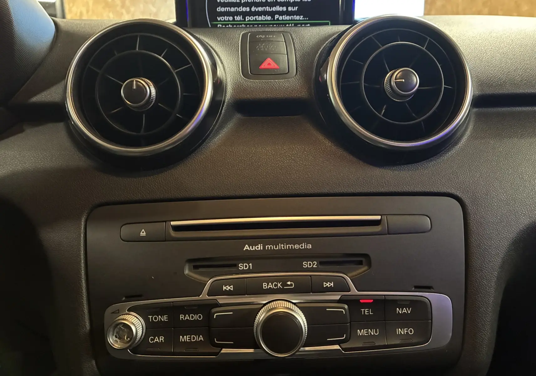 Vue rapprochée du tableau de bord noir de l'Audi A1 2016, mettant en valeur les aérateurs ronds et la console multimédia.