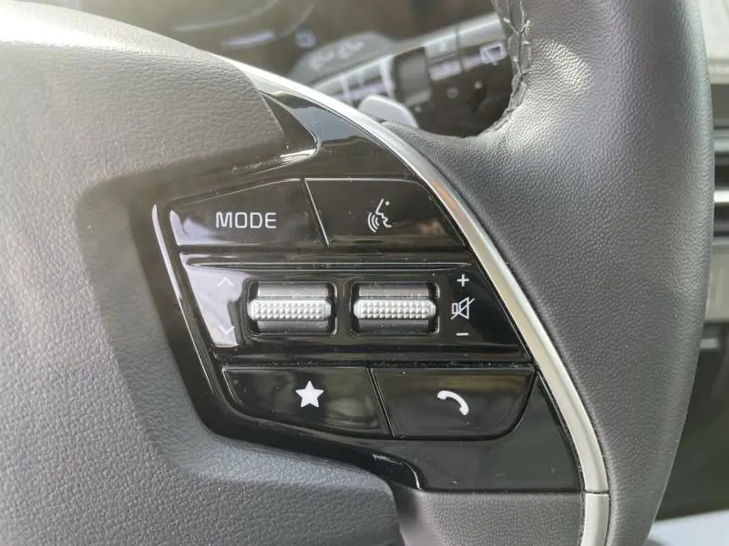 Gros plan sur les commandes multifonctions à gauche du volant du KIA NIRO 2024, finition noire brillante avec boutons tactiles.