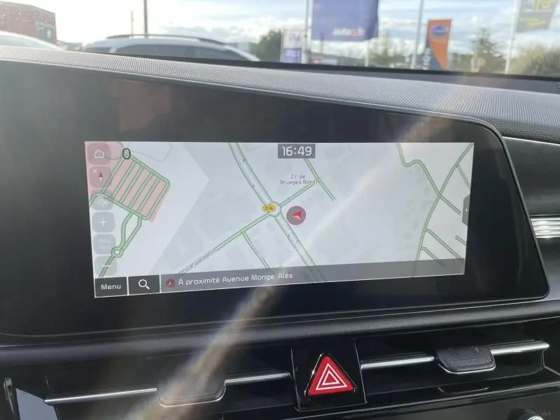 Écran tactile intérieur du Kia Niro 2024 affichant la navigation, avec tableau de bord noir et bouton de signalisation d'urgence rouge.