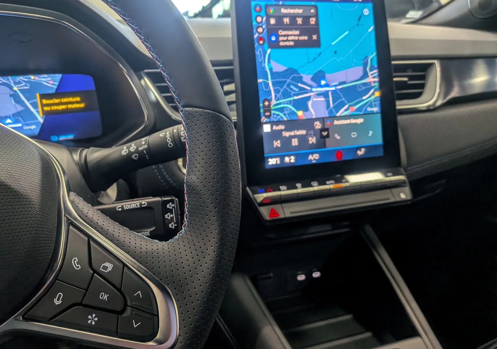 Vue intérieure centrée sur le volant et l’écran tactile du tableau de bord du Renault Symbioz gris Cassiopé, version hybride.