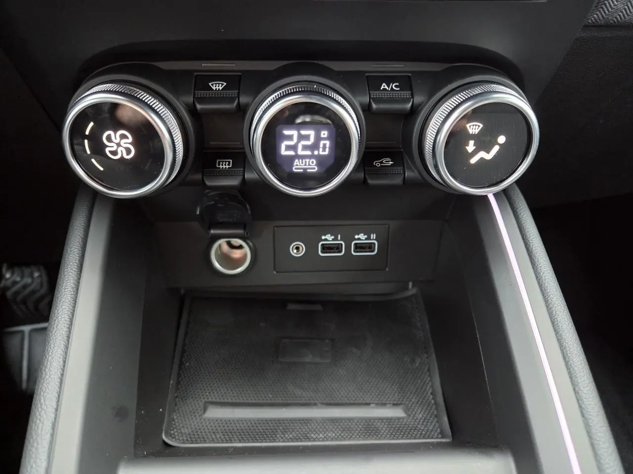 Gros plan sur la console centrale de la Renault Clio 2025 avec commandes de climatisation et ports USB visibles.