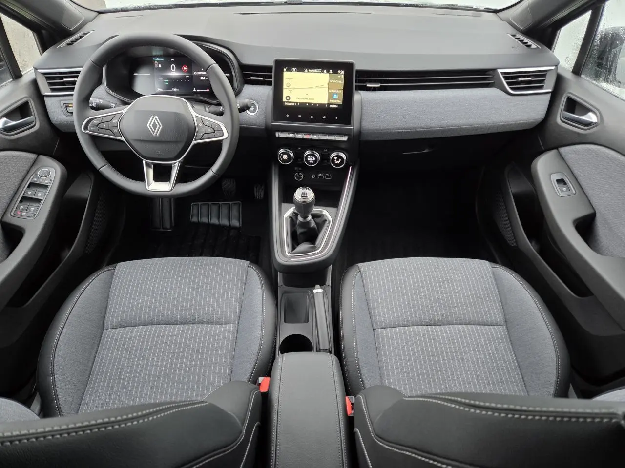 Vue intérieure avant de la Renault Clio 2025 gris schiste, avec volant multifonction, écran tactile et boîte manuelle.