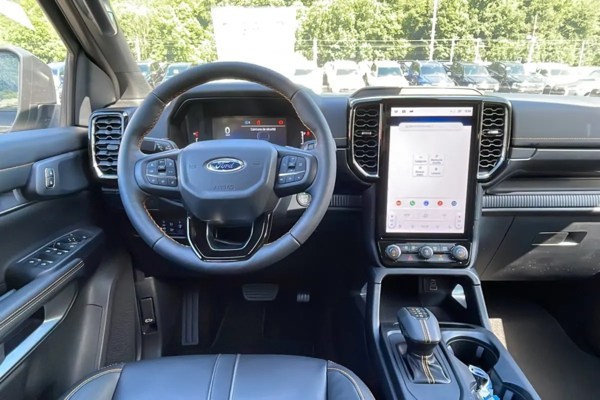 Vue intérieure avant du Ford Ranger 2.0 205 Wildtrak Plus, volant cuir multifonctions et grand écran tactile vertical.