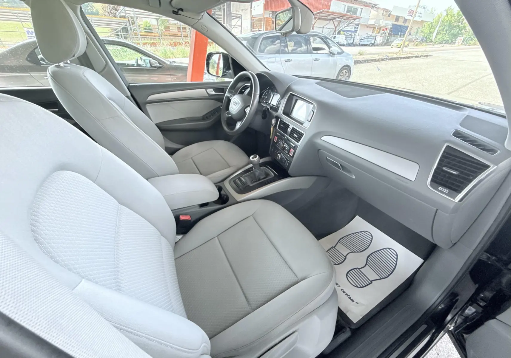 Vue intérieure côté passager de l'Audi Q5 2014 noire, montrant sièges gris clairs et tableau de bord moderne.