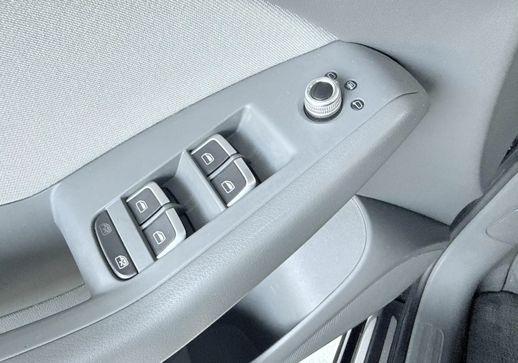 Gros plan sur les commandes des vitres et rétroviseurs côté conducteur d’un Audi Q5 noir de 2014.