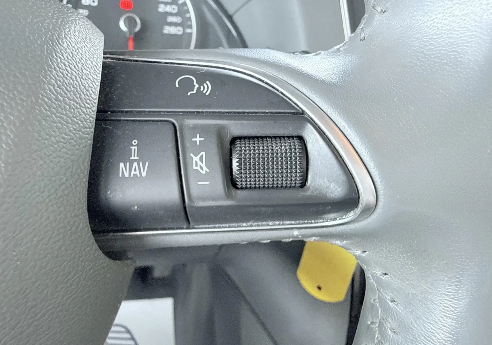 Gros plan sur les commandes de navigation et volume au volant d’un Audi Q5 noir, tableau de bord partiellement visible.