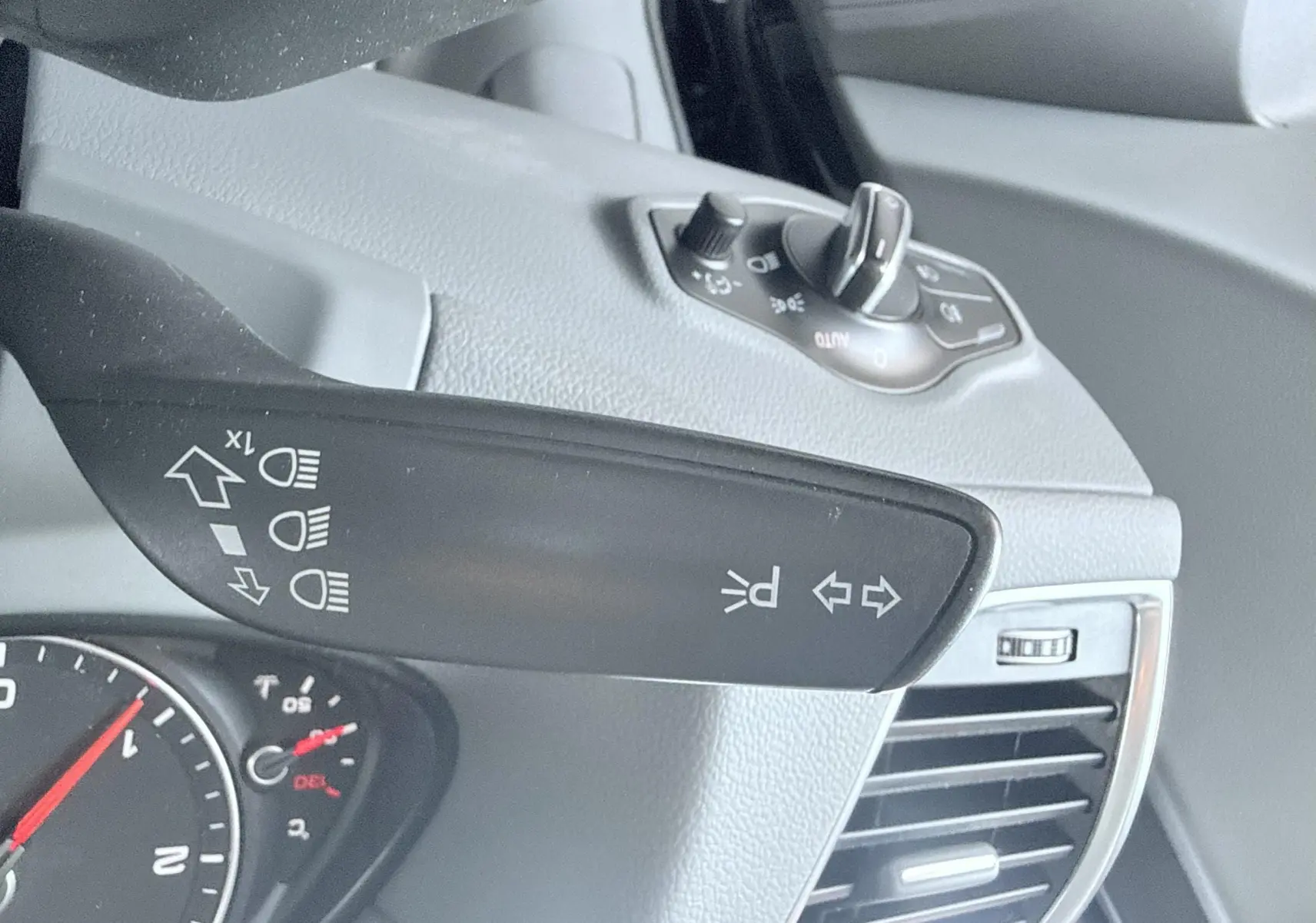 Gros plan sur la commande des clignotants et phares à gauche du volant dans l’habitacle noir de l’Audi Q5 2014.