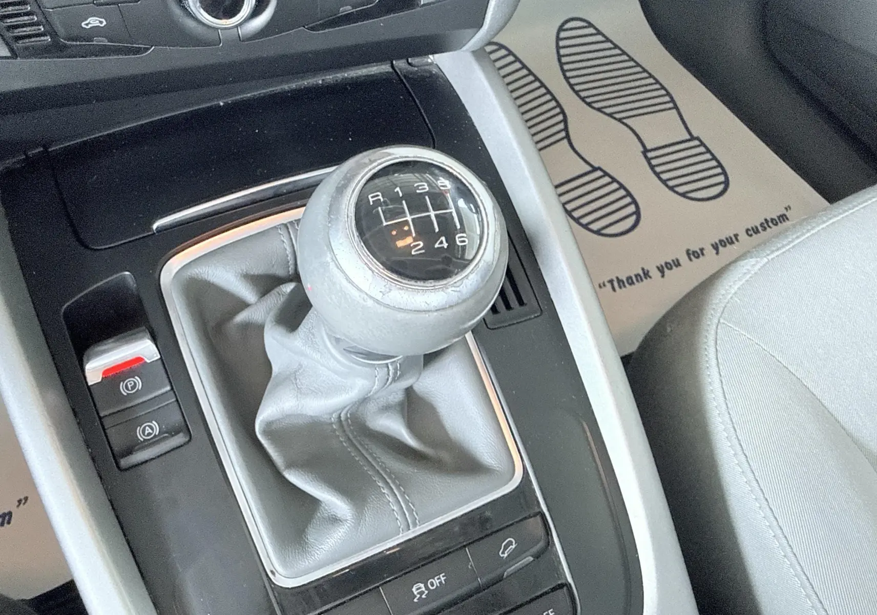 Gros plan sur le levier de vitesses manuel gris de l'Audi Q5, entouré de la console centrale noire et grise.