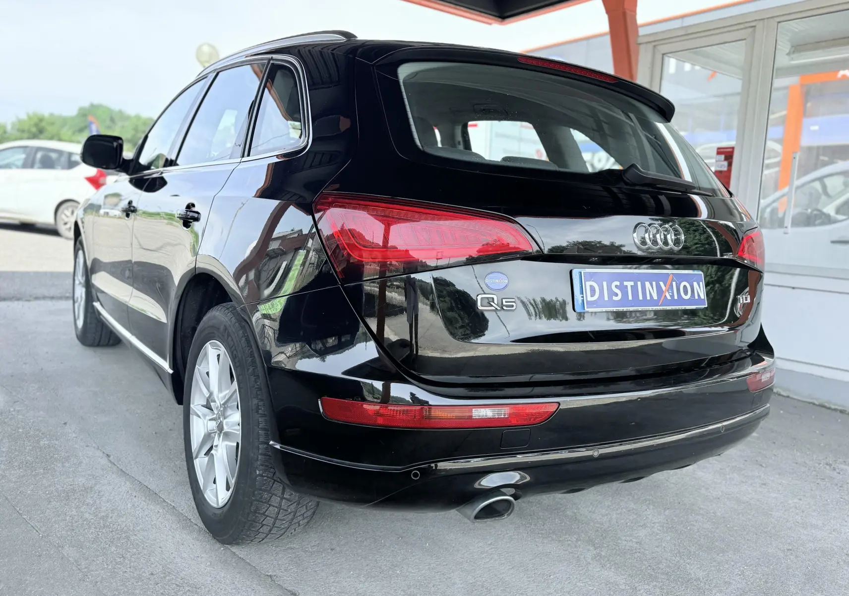 Audi Q5 noir vue 3/4 arrière droit, avec feux arrière rouges et sortie d’échappement visible.