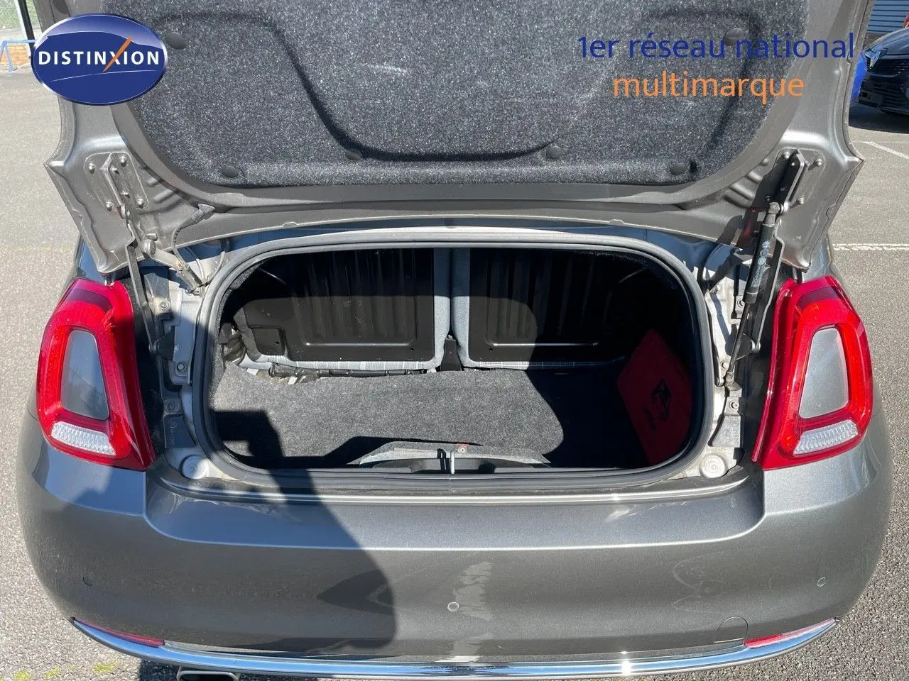 Coffre ouvert vu de l'arrière d'une Fiat 500C 1.2 69CH Lounge gris métallisé Electroclash, feux arrière rouges visibles.