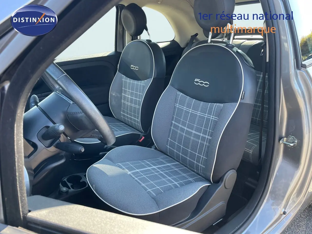 Vue intérieure côté conducteur de la FIAT 500C grise avec sièges tissu gris à motif écossais et logo 500 brodé.