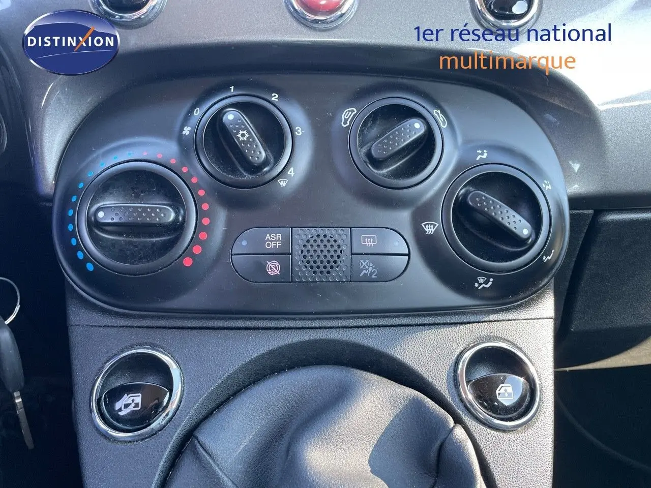 Détail du tableau de bord de la Fiat 500C 2019 montrant les commandes de climatisation et les boutons de lève-vitres.