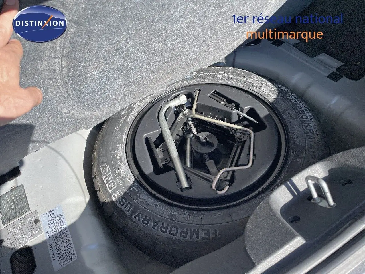 Gros plan sur la roue de secours et les outils de bord dans le coffre d'une Fiat 500C gris électroclash.