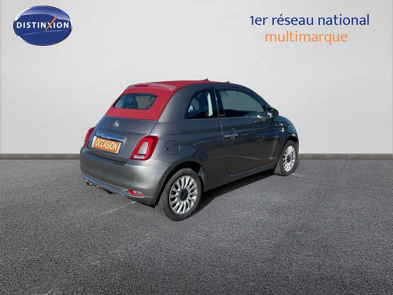 Fiat 500C grise électroclash vue 3/4 arrière côté droit avec toit rouge cabriolet fermé sur parking.