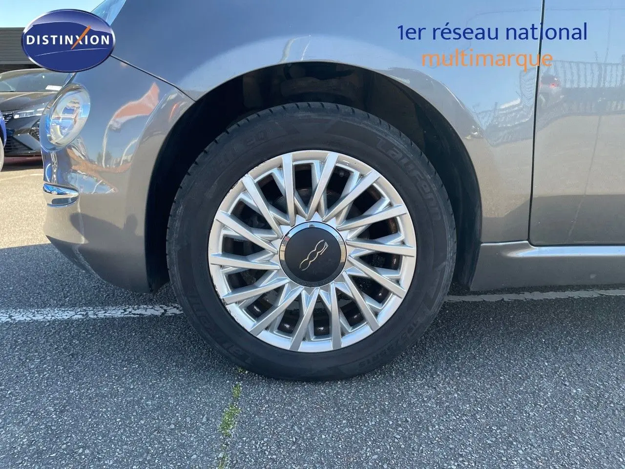 Gros plan sur la roue avant gauche d'une Fiat 500C grise électroclash avec jante alu multibranches.
