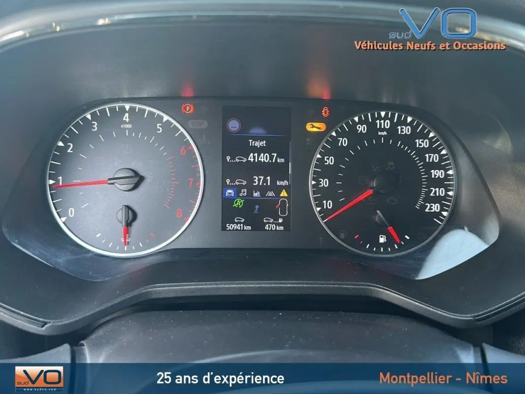 Tableau de bord de Renault Clio bleu foncé 2023, affichant compteur et écran digital avec kilométrage et alertes.