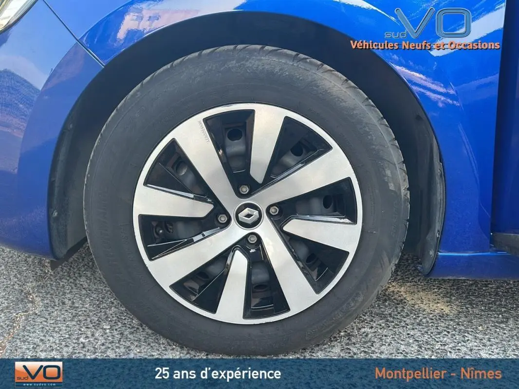 Gros plan sur la roue avant gauche d'une Renault Clio bleu foncé 2023 avec jante alliage au design moderne.