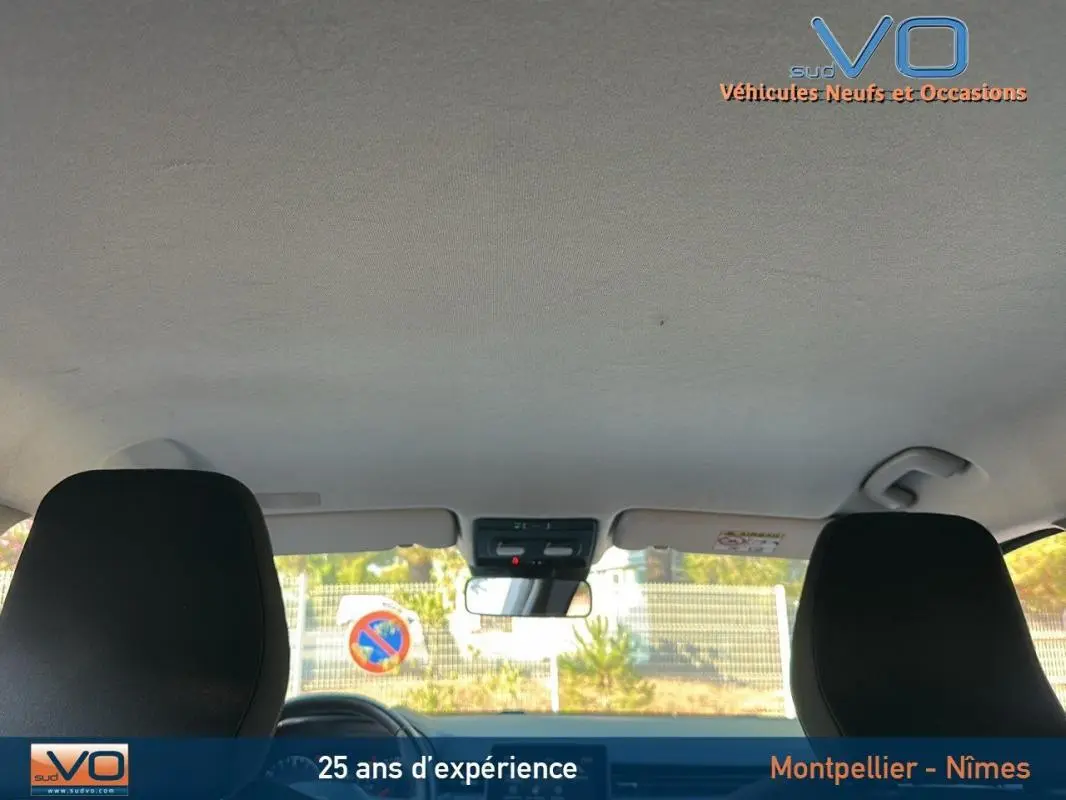 Vue intérieure avant de la Renault Clio 2023, sièges noirs et pare-brise avec rétroviseur central visible.