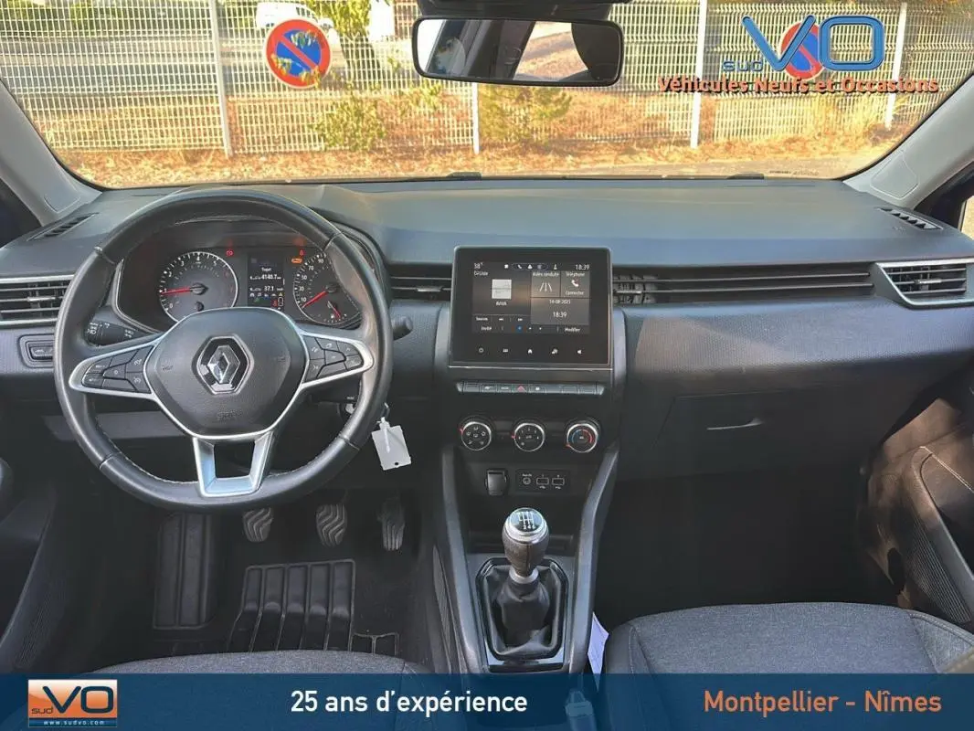 Vue intérieure avant de la Renault Clio V TCe 90 Equilibre 2023 avec volant multifonction, boîte manuelle et écran tactile central.