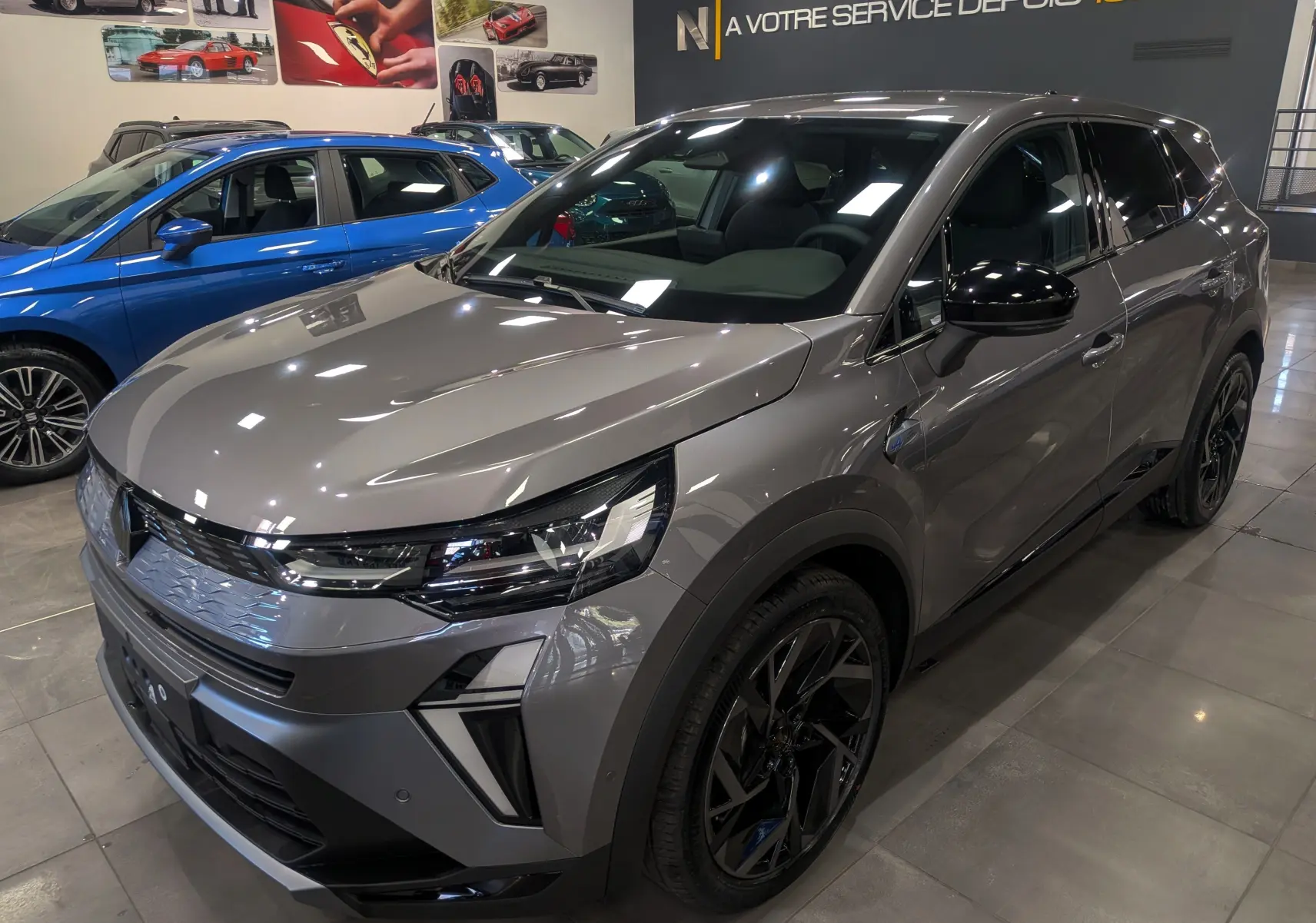 Vue 3/4 avant droite d'une Renault SYMBIOZ gris Cassiopé avec jantes noires et détails noirs brillants en showroom.