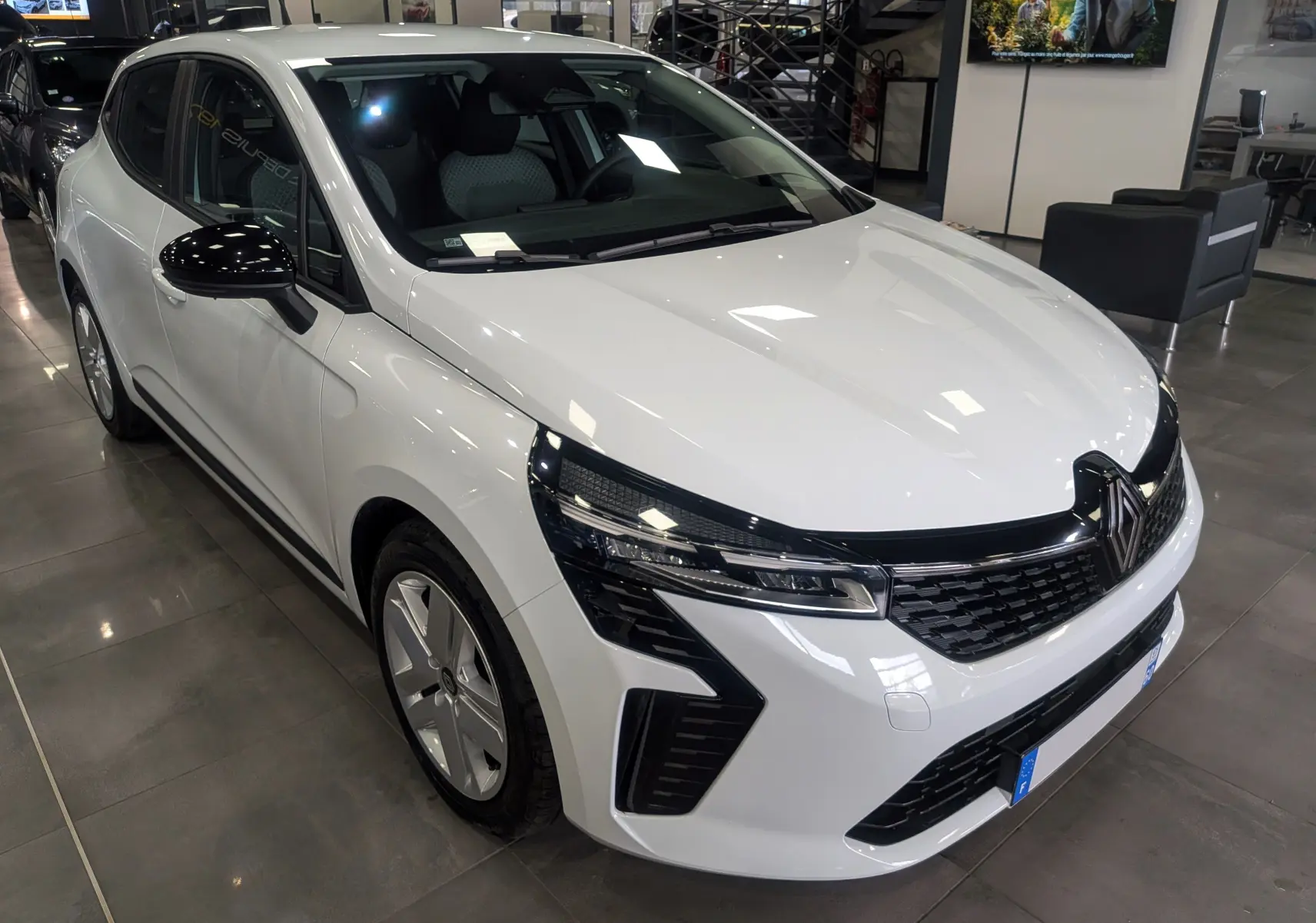 Renault Clio V Blue dCi 100 CH Evolution blanc glacier vue 3/4 avant droit en showroom, détails noirs contrastants.