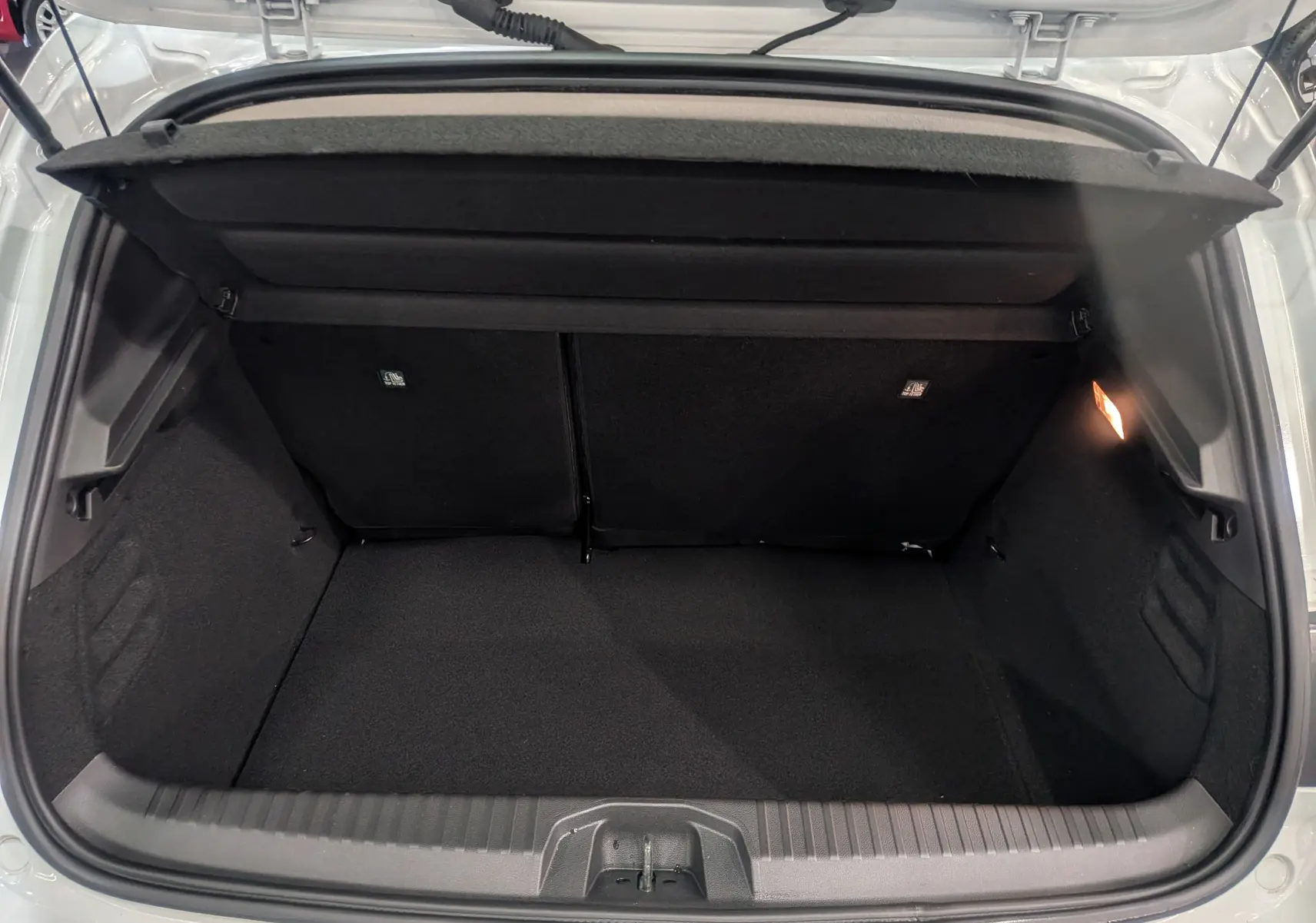 Coffre ouvert vu de l'arrière d'une Renault Clio V Blanc Glacier, montrant un espace de rangement noir et propre.