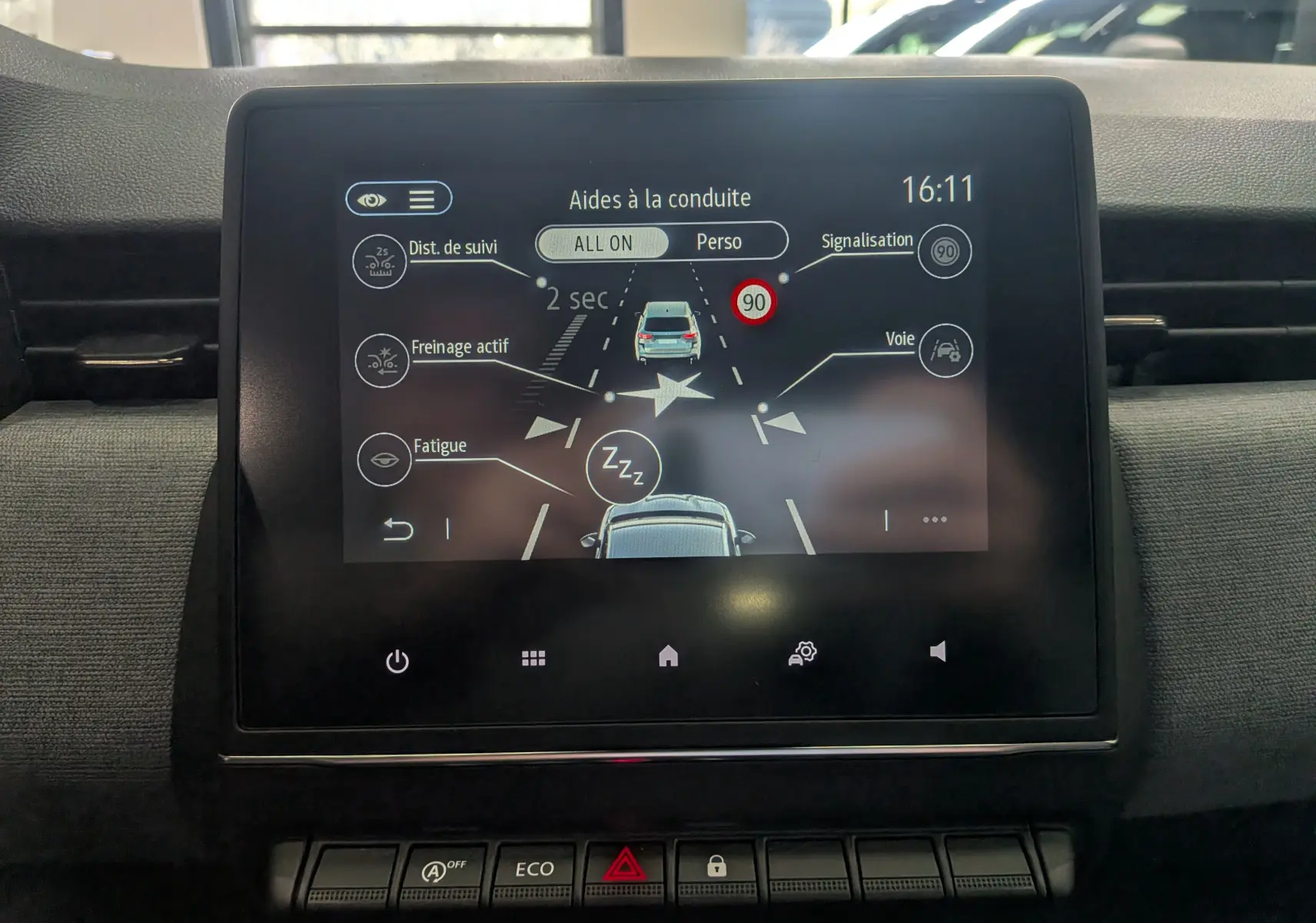 Écran tactile central de la Renault Clio V blanc glacier montrant les aides à la conduite en mode jour.