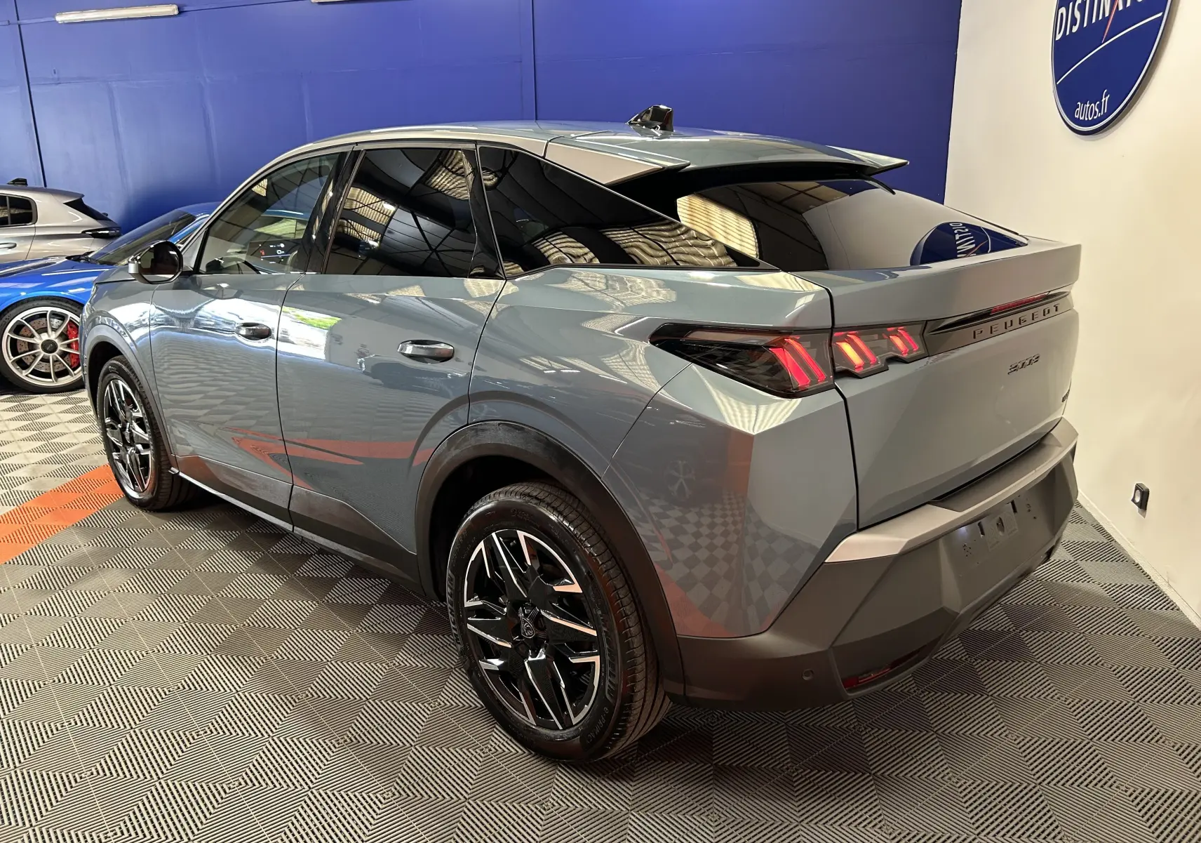 Vue 3/4 arrière droite du Peugeot 3008 Hybrid 2024 en Bleu Ingaro avec feux arrière LED et jantes noires brillantes.