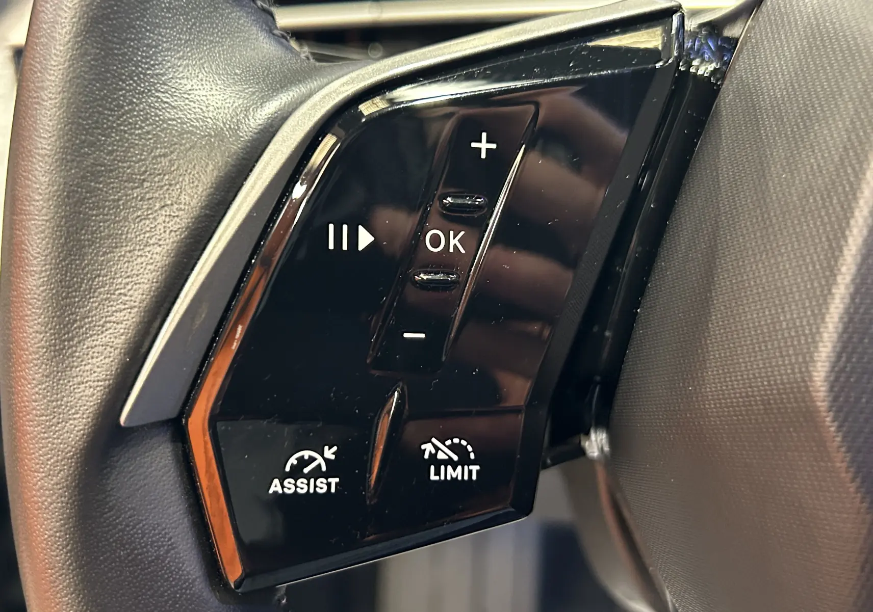 Gros plan sur les commandes du volant noir du Peugeot 3008 III Hybrid 136 e-DCS6 Allure, boutons multifonctions visibles.