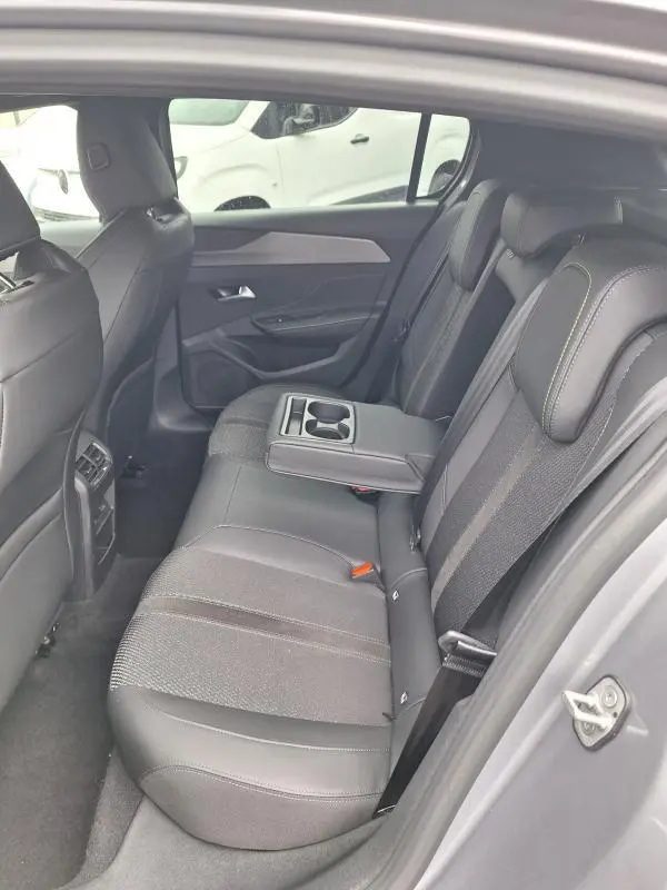 Vue intérieure côté droit des sièges arrière gris du Peugeot 308 Hybrid 145 e-DCS6 GT avec accoudoir central et porte-gobelets.