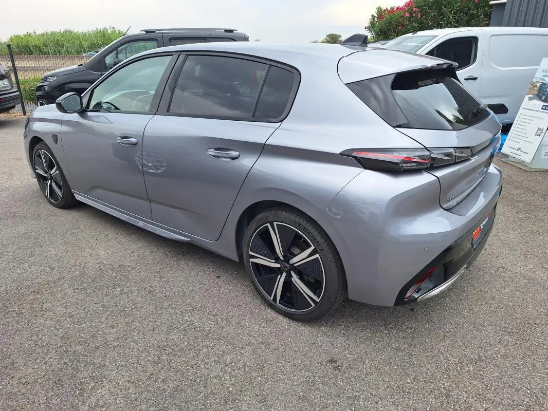 Peugeot 308 Hybrid gris vue 3/4 arrière droit, jantes alliage 18 pouces et feux arrière LED distinctifs.