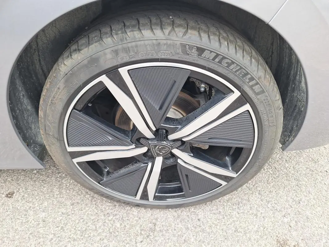 Gros plan sur la jante alliage 18 pouces noire et argentée d'une Peugeot 308 Hybrid 145 e-DCS6 GT gris.