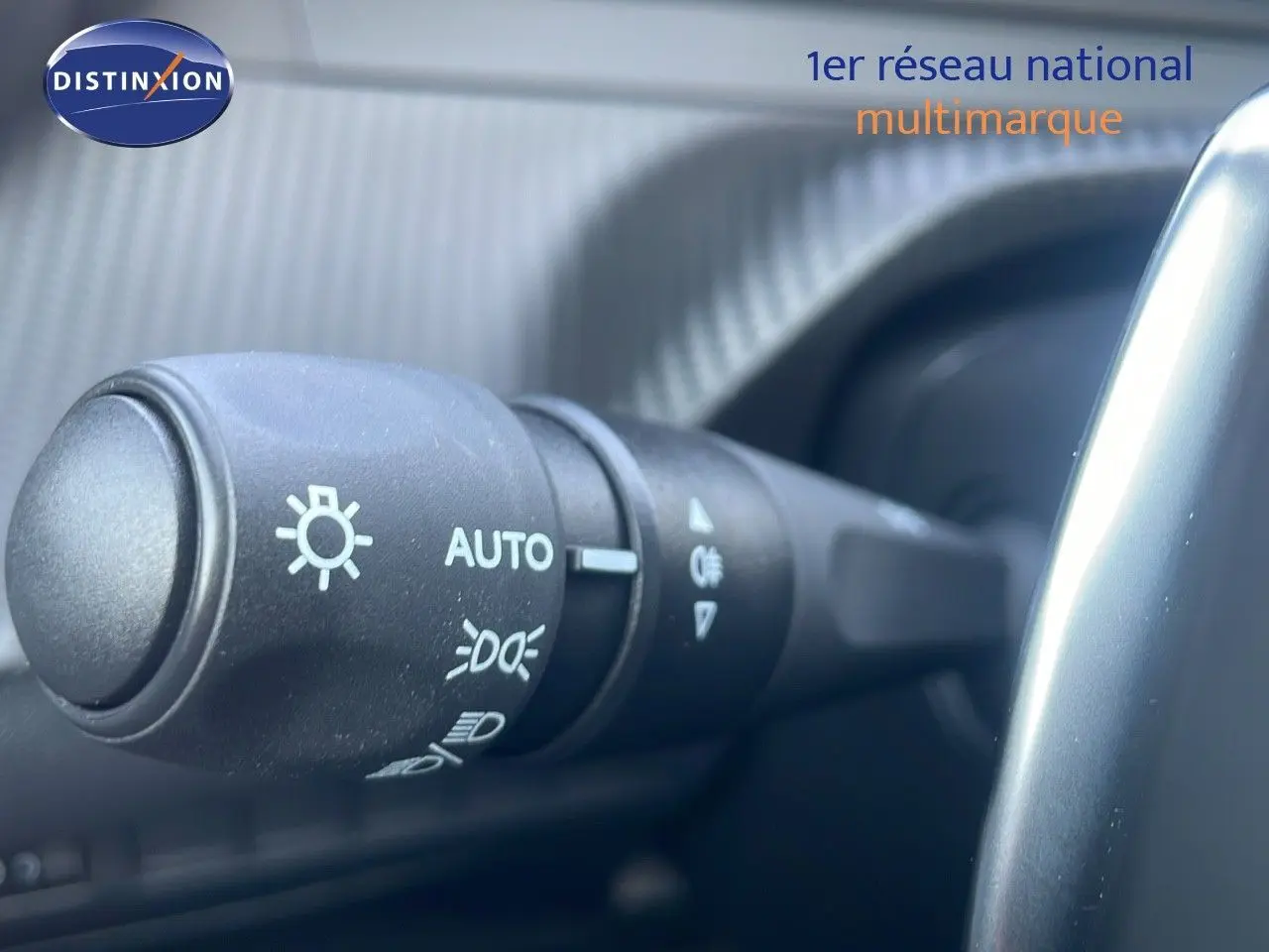 Gros plan sur la commande des phares du Peugeot 2008 gris Artense, côté gauche du volant, intérieur moderne.