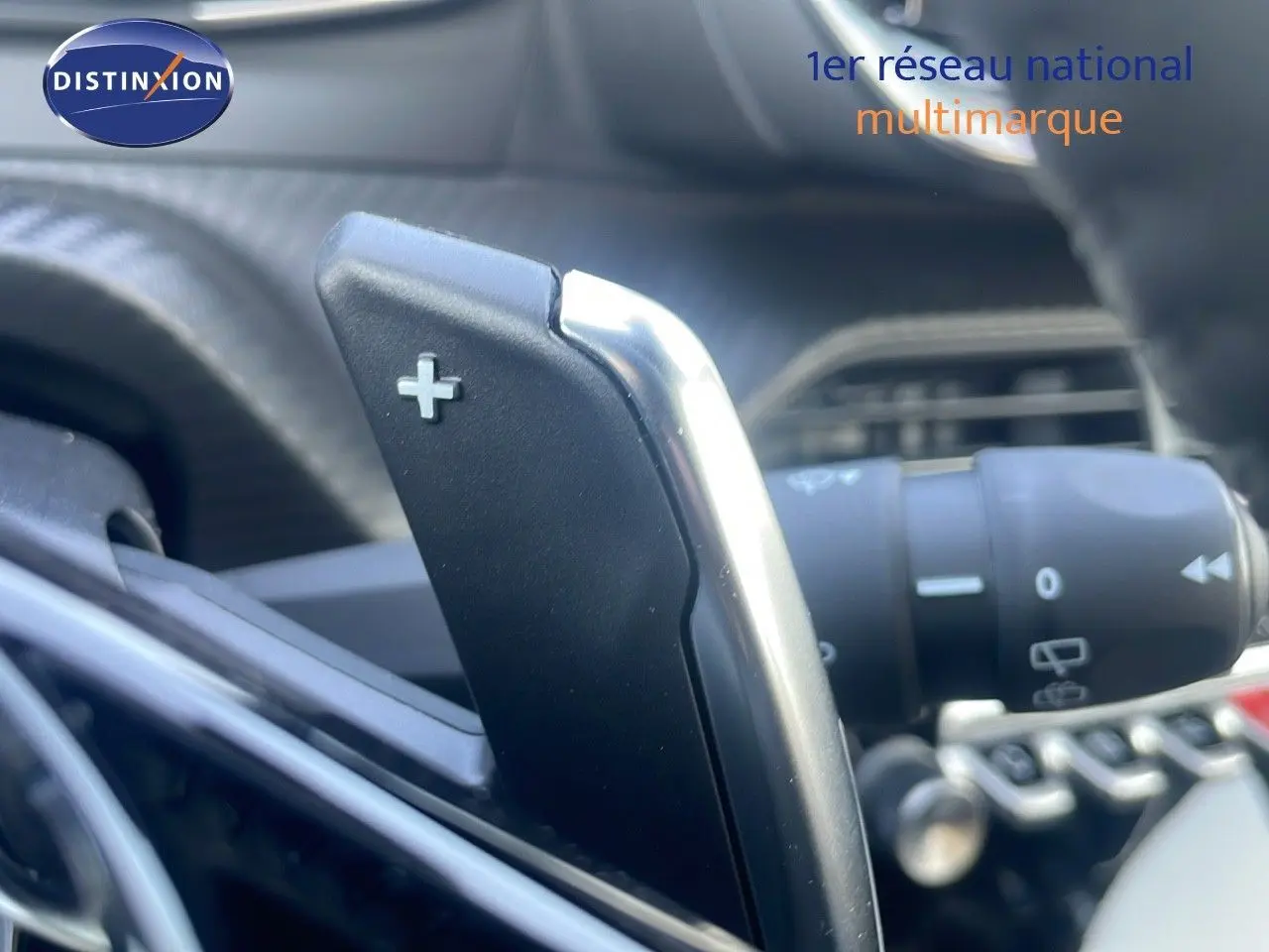 Gros plan sur la palette de changement de vitesse + du Peugeot 2008 gris Artense, intérieur moderne et commandes au volant.