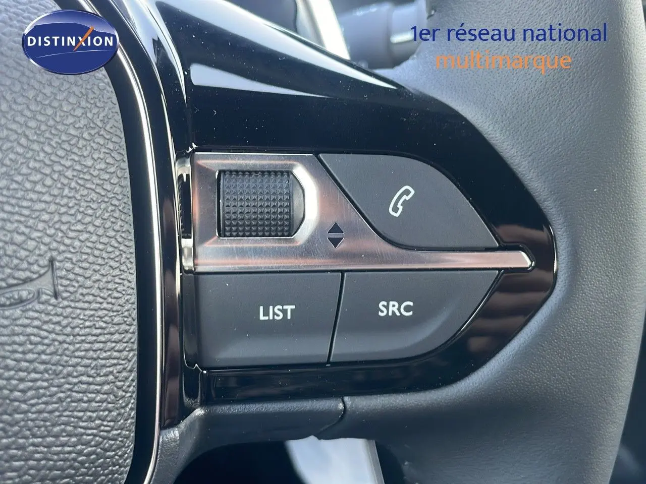 Gros plan sur les commandes gauche du volant du Peugeot 2008 Hybrid gris Artense, boutons LIST, SRC et téléphone.