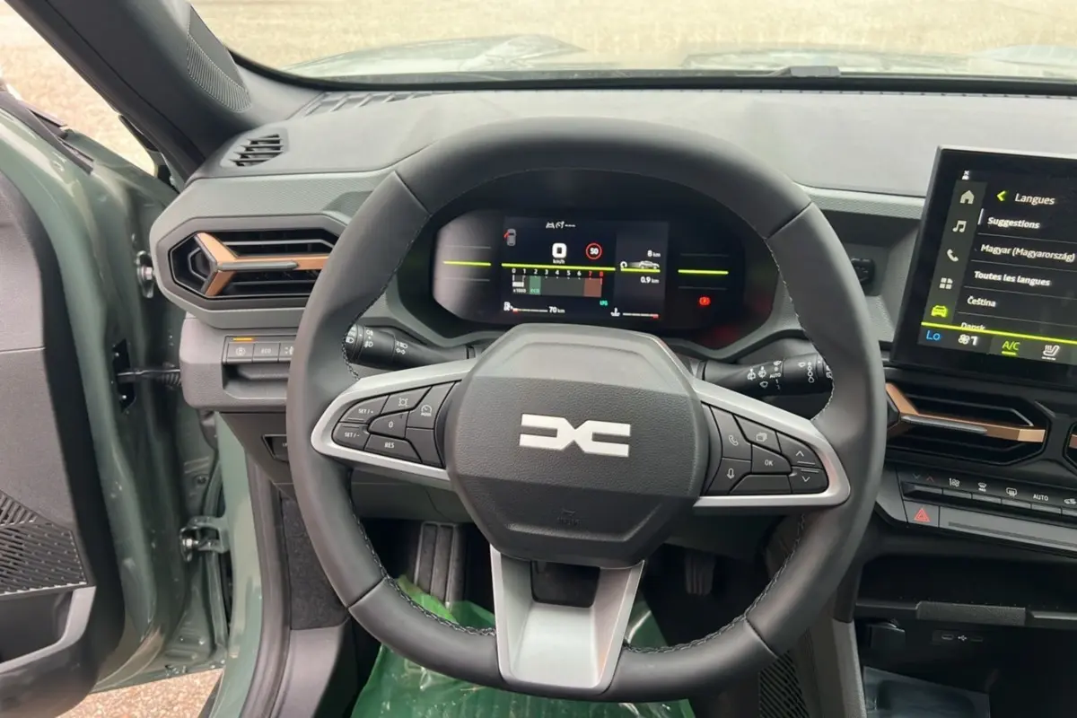 Vue intérieure centrée sur le volant du Dacia Duster 2025 kaki lichen, avec tableau de bord numérique et écran tactile visible.