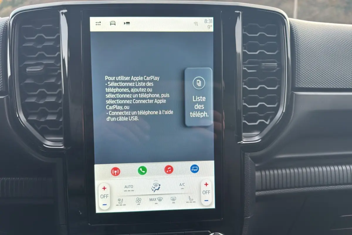 Écran tactile central du Ford Ranger blanc glacier 2025 affichant les instructions Apple CarPlay, entouré de grilles d'aération noires.
