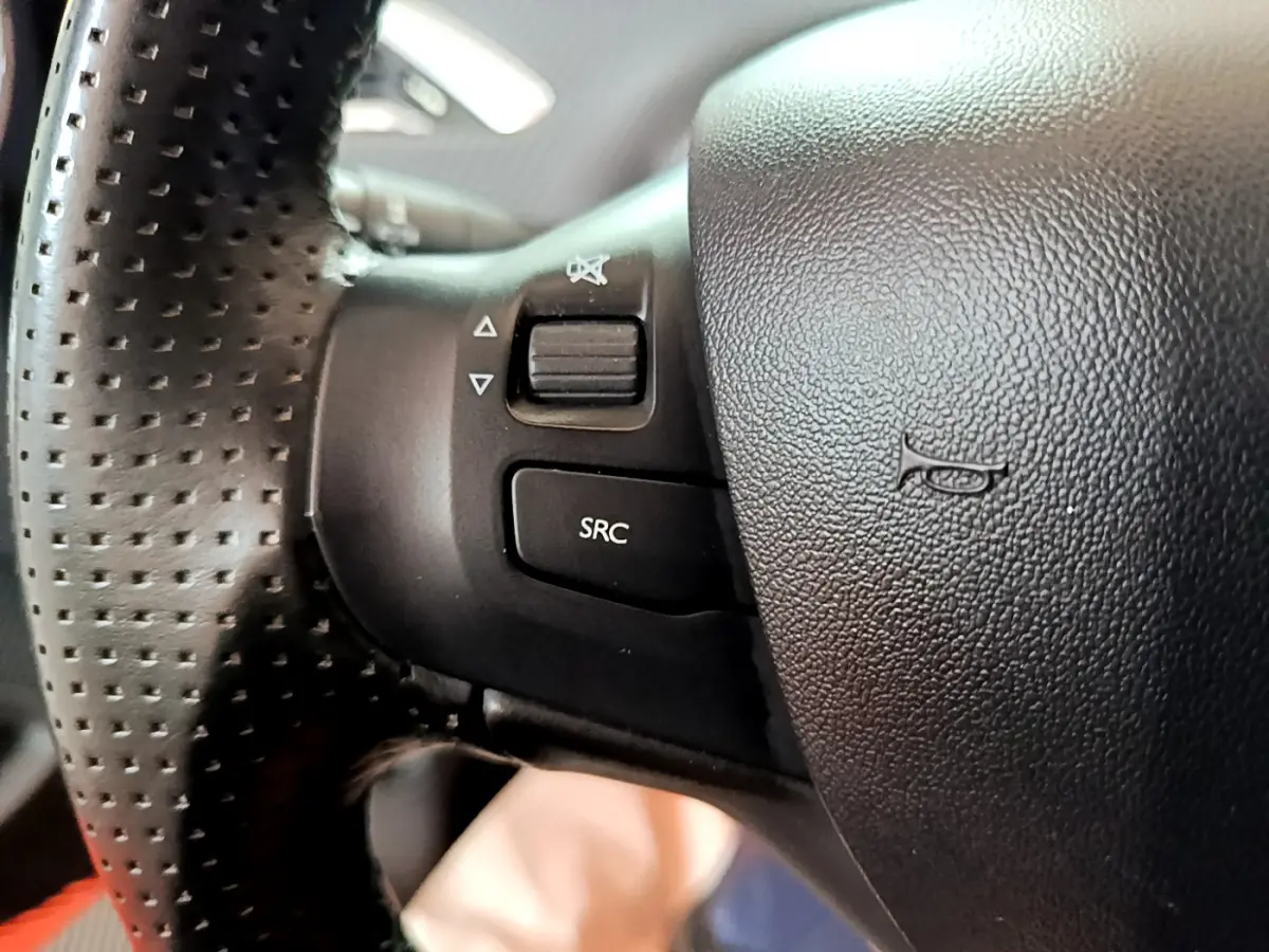 Gros plan sur le volant cuir perforé du Peugeot 2008 2019, avec commandes audio intégrées visibles.