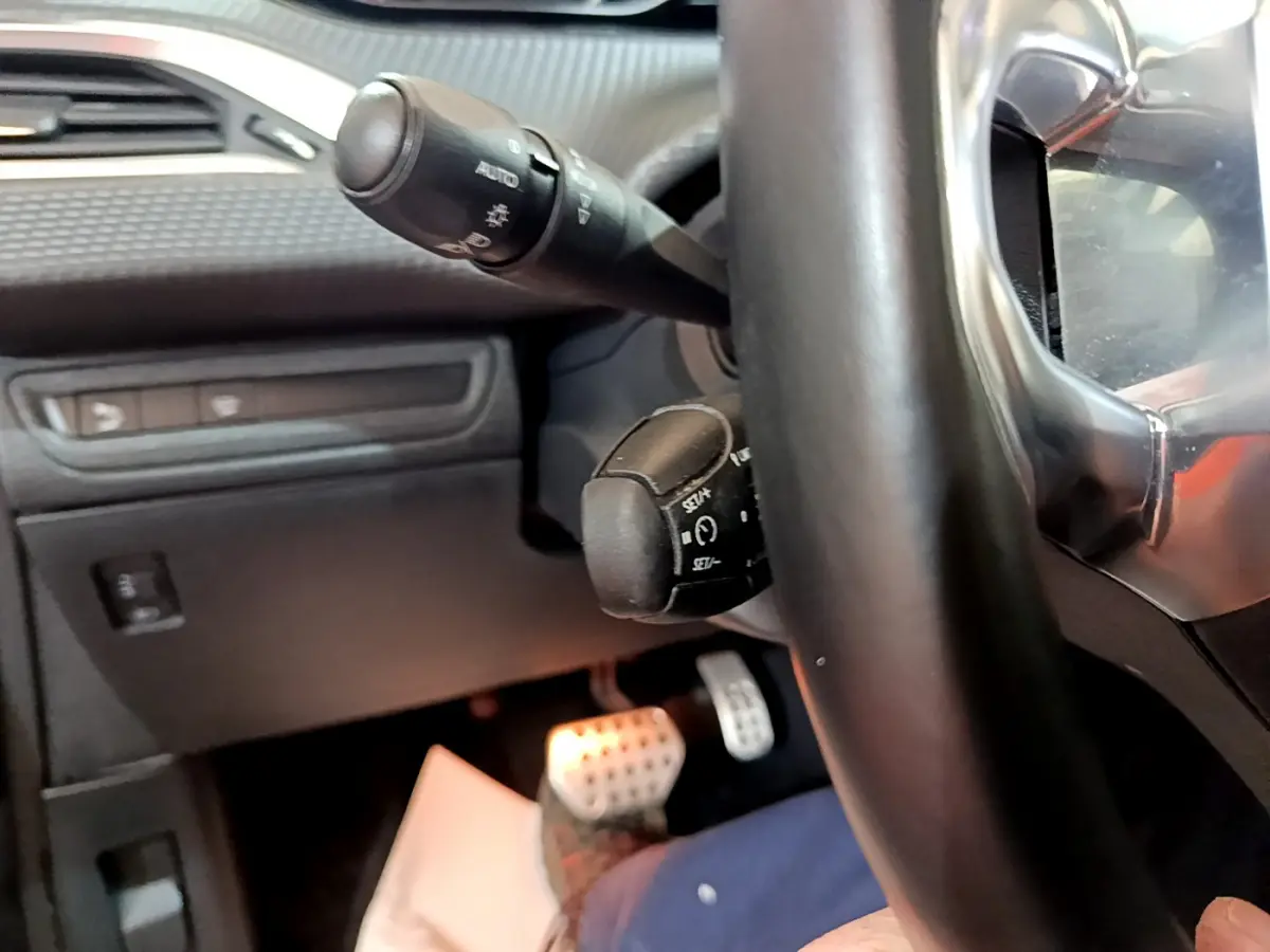 Gros plan sur le volant cuir et les commandes de régulateur de vitesse du Peugeot 2008 gris foncé, intérieur conducteur.