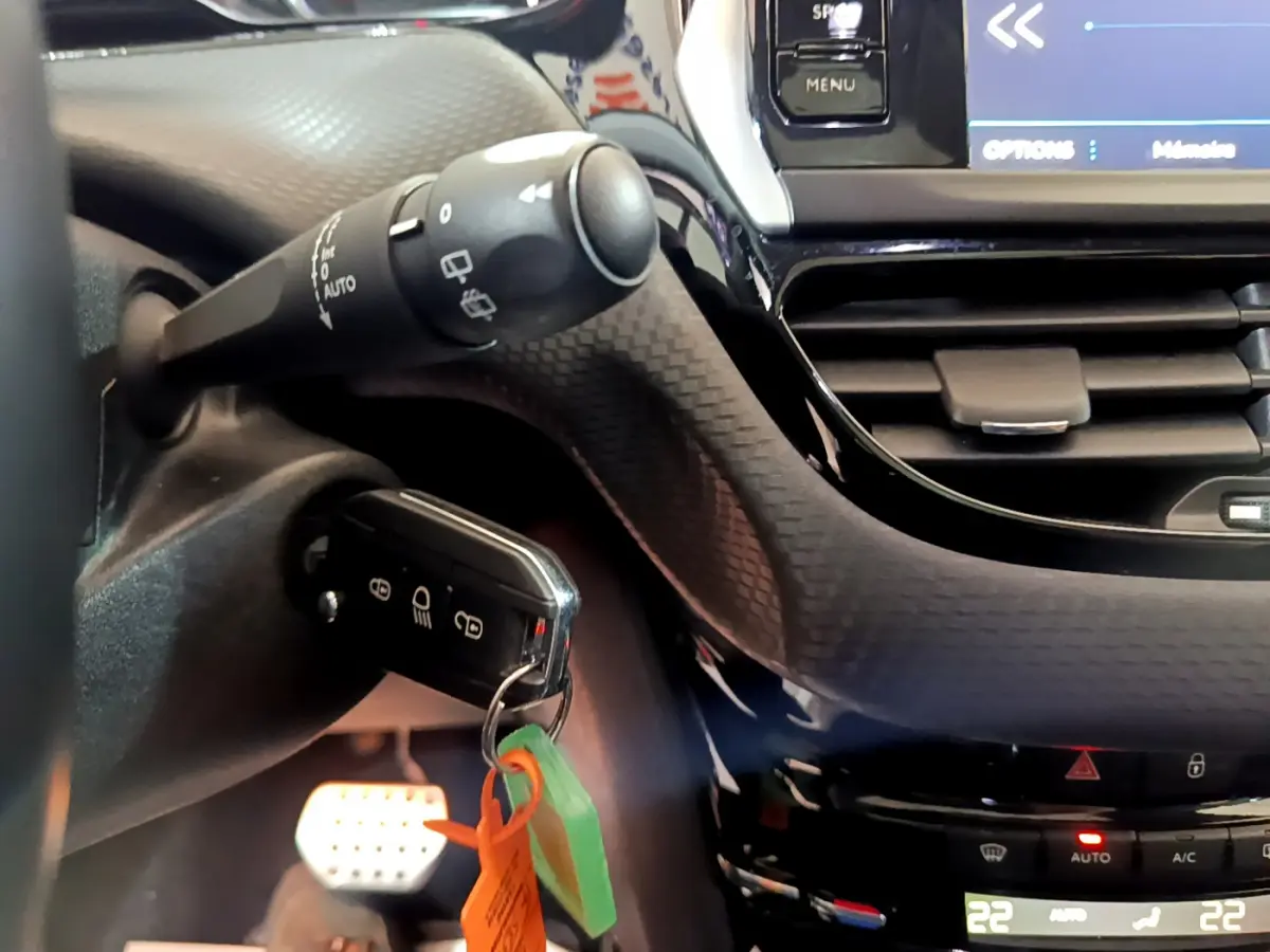 Gros plan sur le tableau de bord et la clé insérée du Peugeot 2008 gris foncé, avec commandes et écran tactile visibles.
