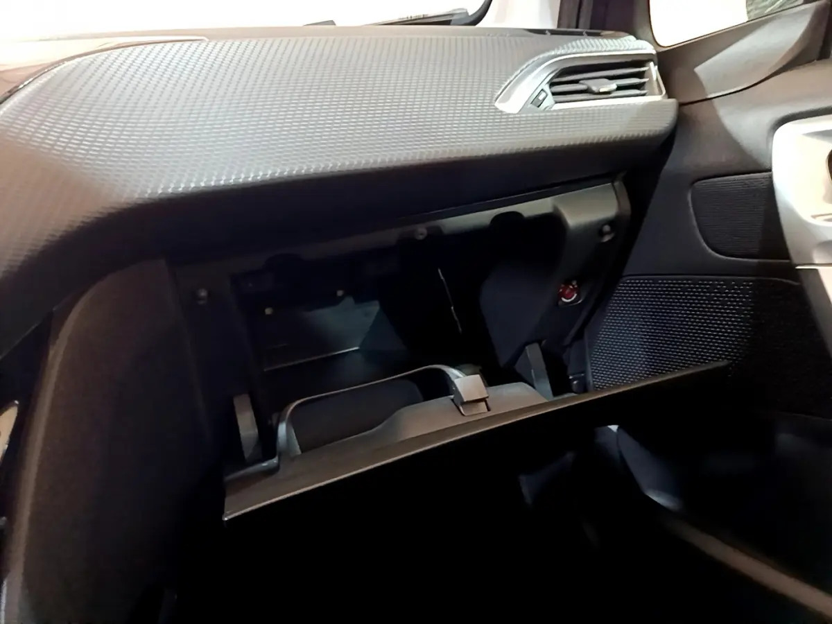 Intérieur du Peugeot 2008 gris foncé, vue côté passager sur la boîte à gants ouverte et tableau de bord texturé.