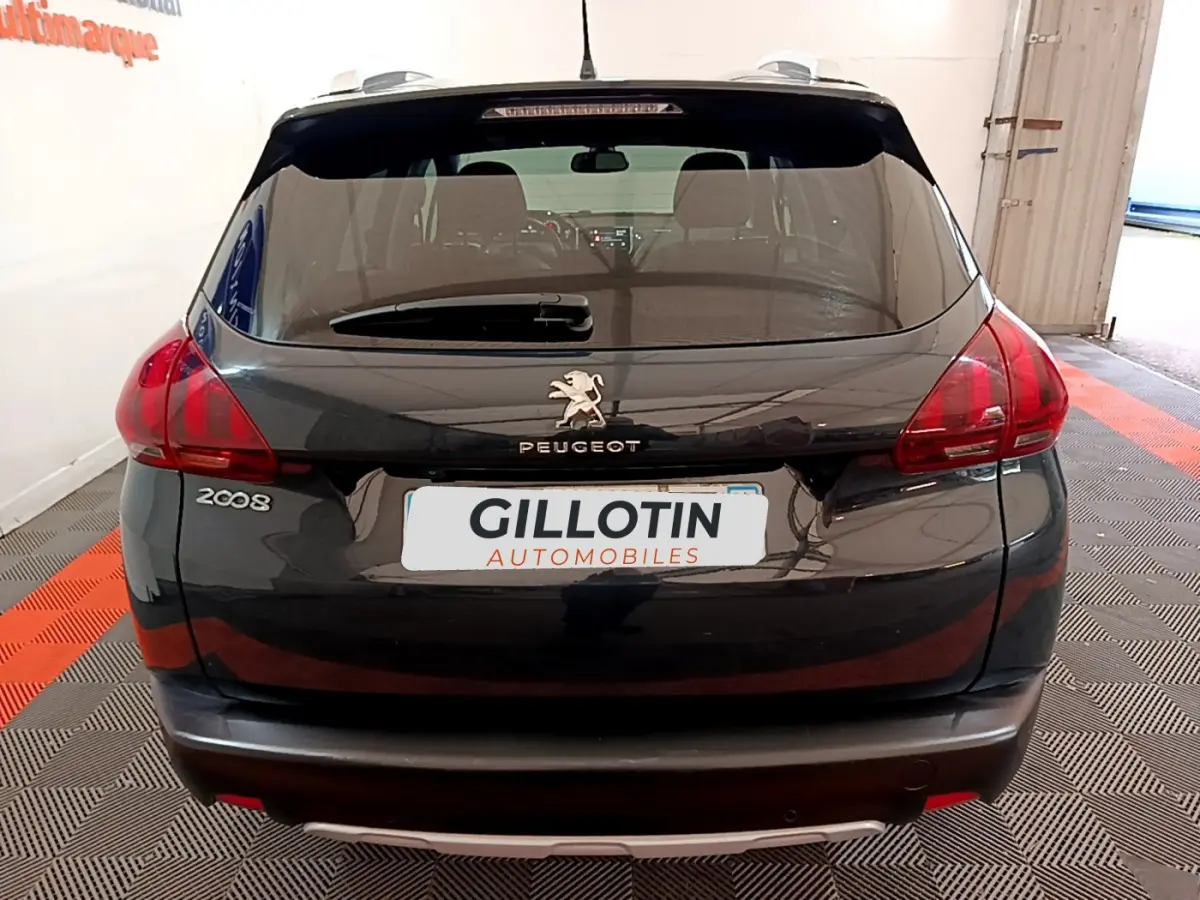 Vue arrière d'un Peugeot 2008 gris foncé avec feux rouges et logo lion sur le hayon dans un garage.