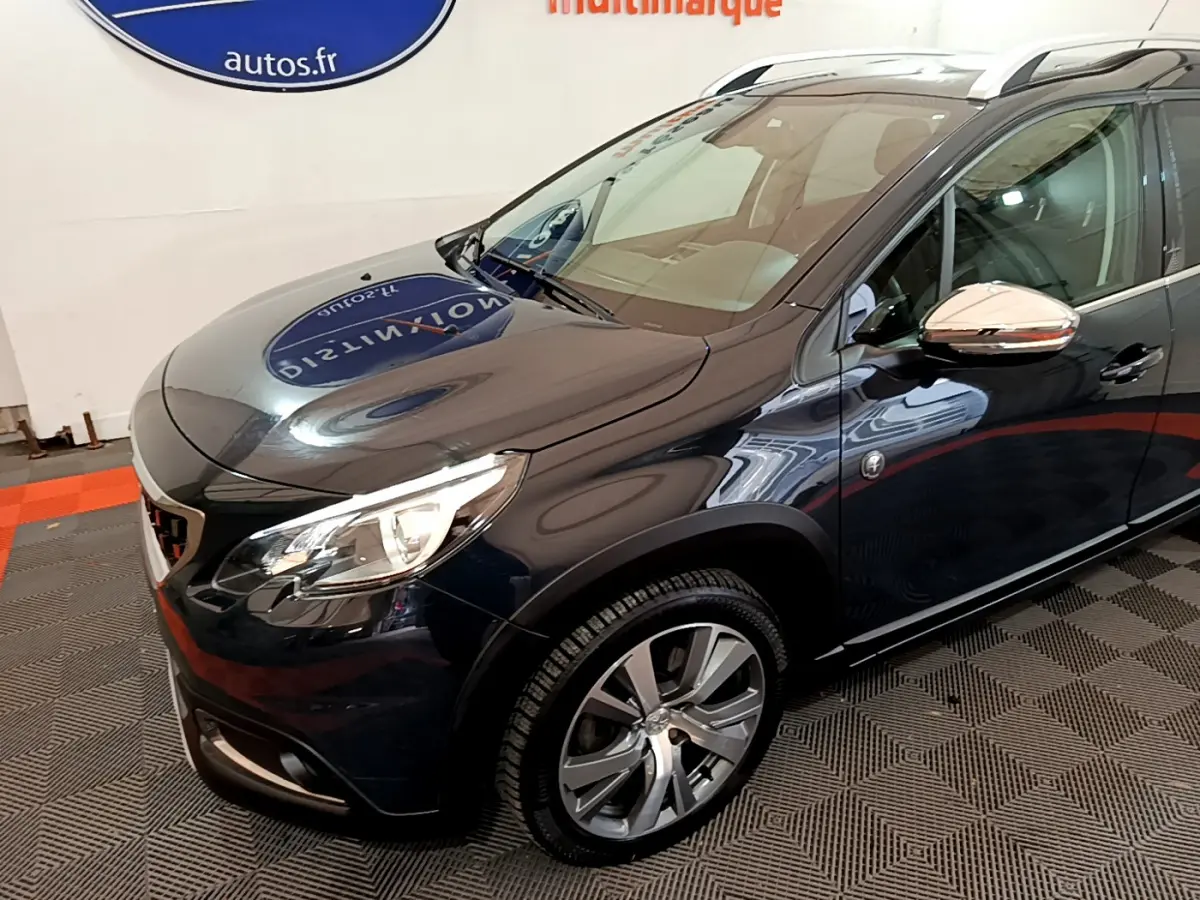 Vue 3/4 avant droit d'un Peugeot 2008 gris foncé avec jantes alliage et rétroviseurs chromés.