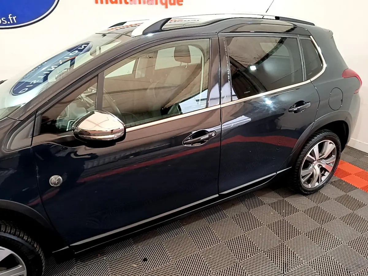 Profil côté gauche d'un Peugeot 2008 gris foncé avec rétroviseurs chromés et jantes alliage visibles.