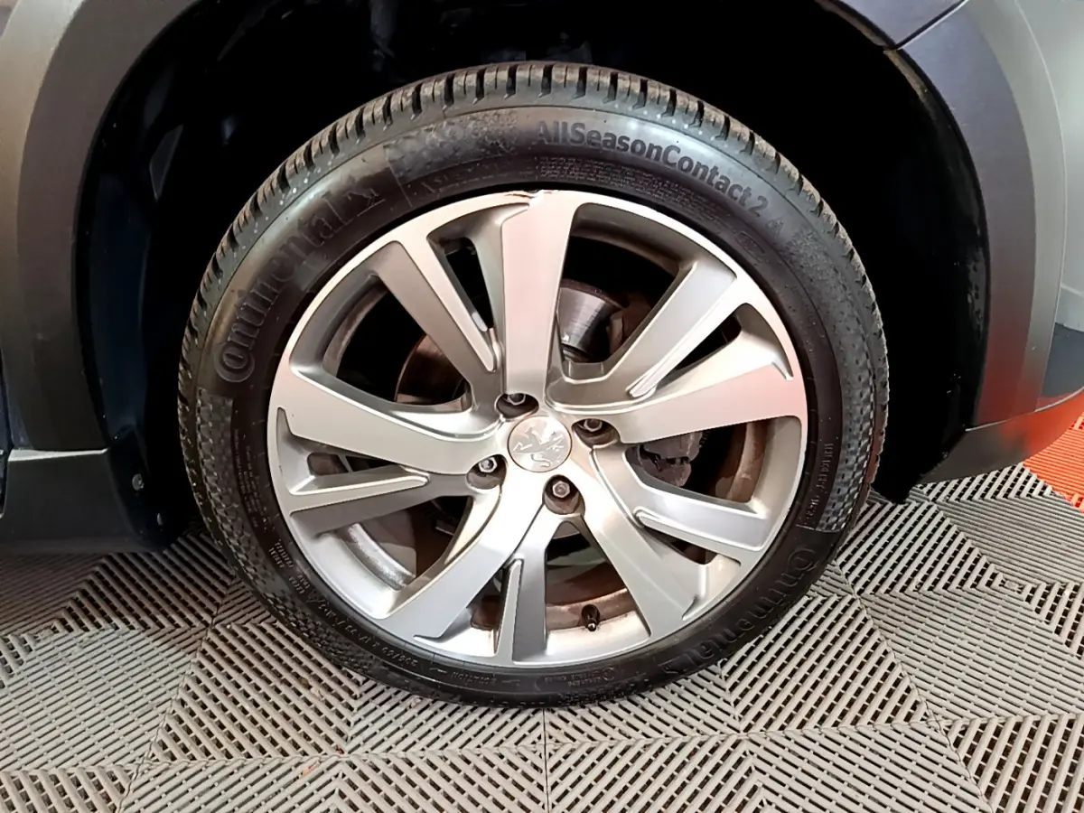 Gros plan sur la roue avant gauche avec jante alliage argentée du Peugeot 2008 gris foncé 2019 Crossway