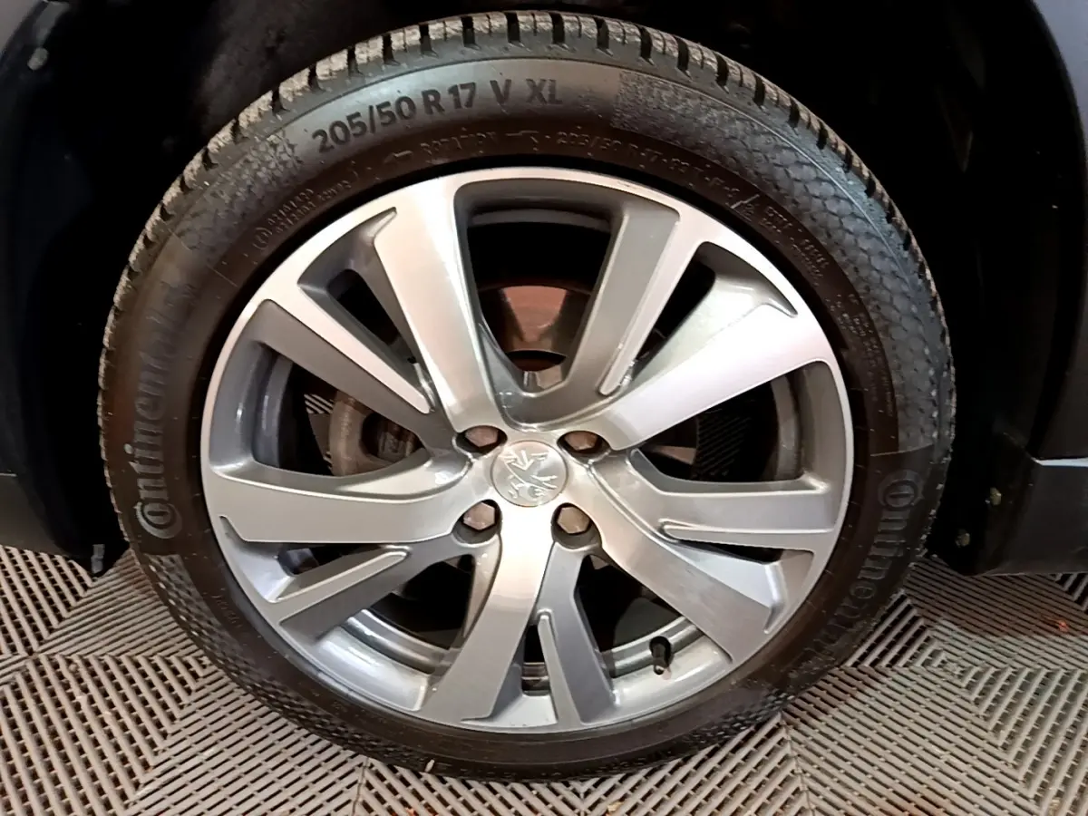 Gros plan sur la jante alliage argentée et pneu Continental du côté avant droit d'un Peugeot 2008 gris foncé.