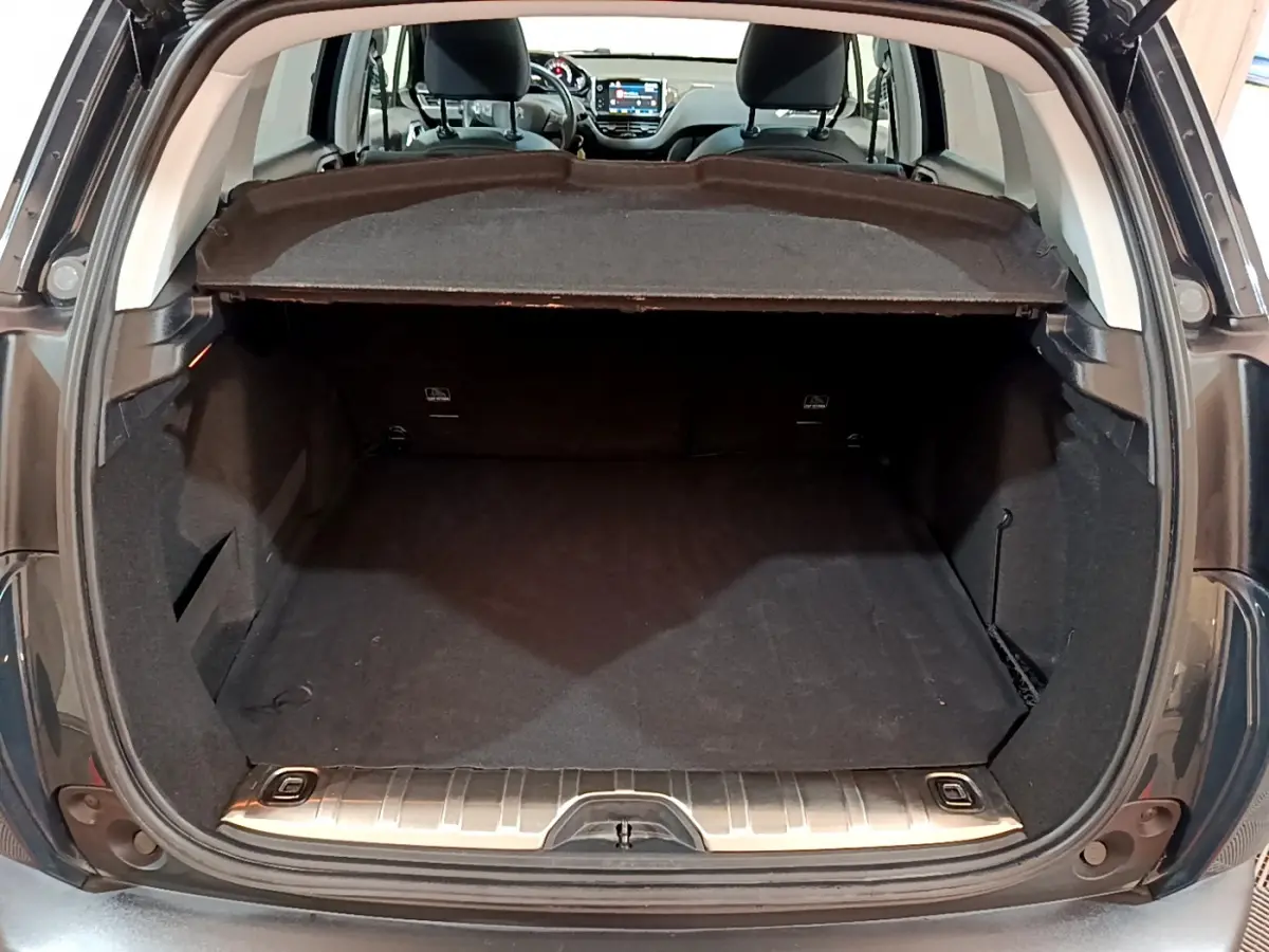 Coffre ouvert d’un Peugeot 2008 gris foncé, vue arrière montrant l’espace de chargement et l’intérieur avant avec écran tactile.