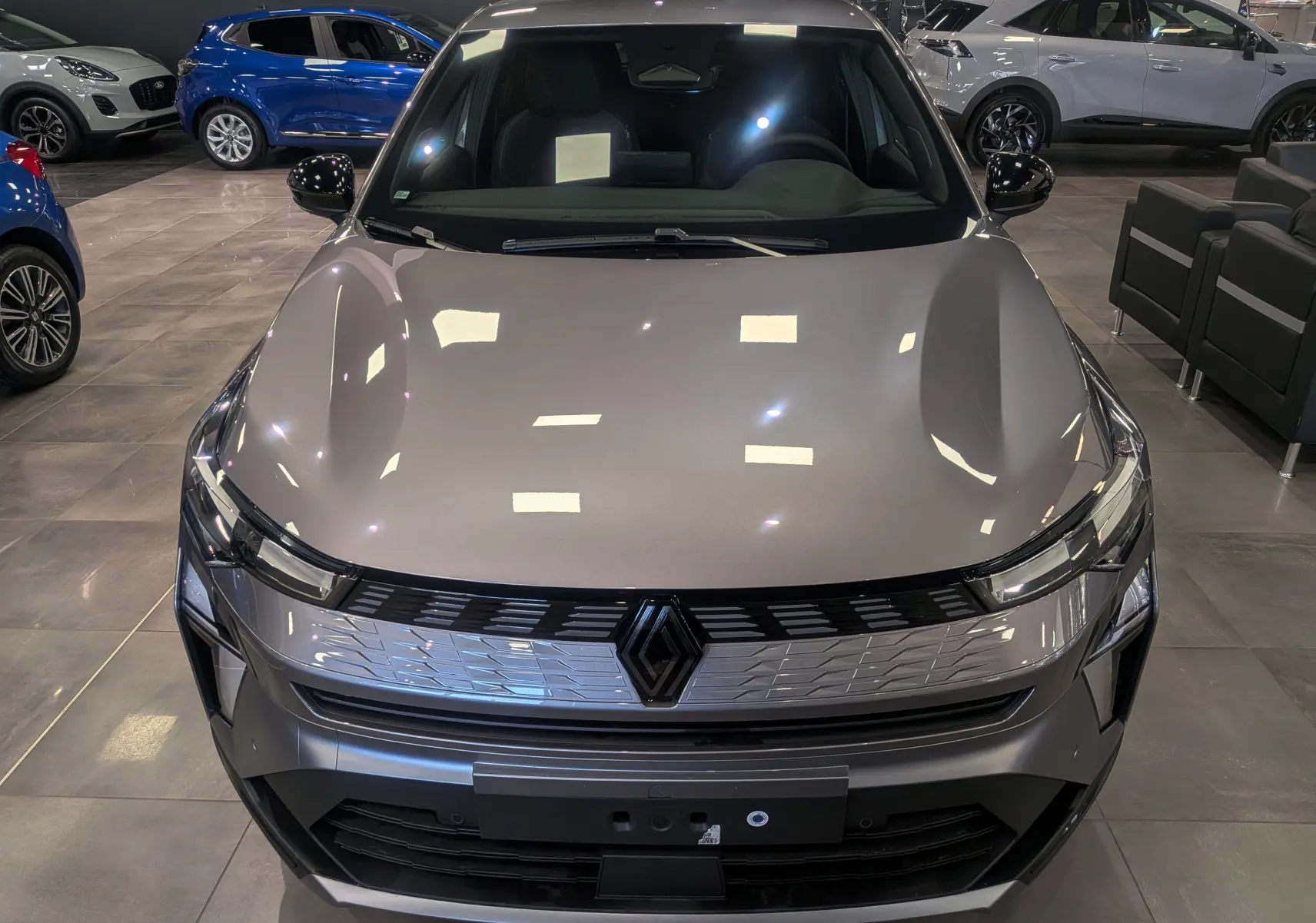 Vue avant rapprochée du Renault SYMBIOZ E-TECH gris Cassiopé, mettant en valeur sa calandre moderne et ses phares fins.